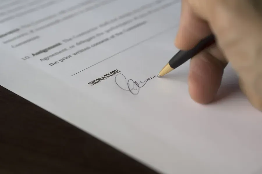Mano firmando un contrato de arrendamiento con pluma